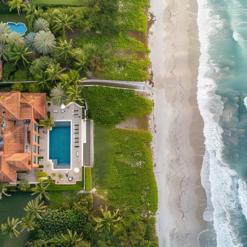 An aerial view of a luxurious beachfront house with a swimming pool.